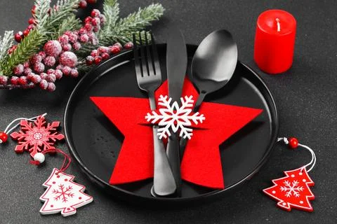 Festive Christmas table setting, dinnerware. Black plate and cutlery in red.. Photos