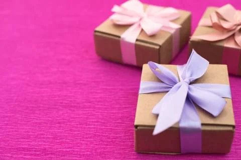 Festive composition three Kraft boxes with gifts on bright pink background. Stock Photos