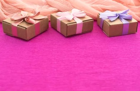 Festive composition three Kraft boxes with gifts on bright pink background. Stock Photos