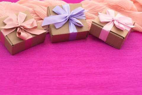 Festive composition three Kraft boxes with gifts on bright pink background. Stock Photos