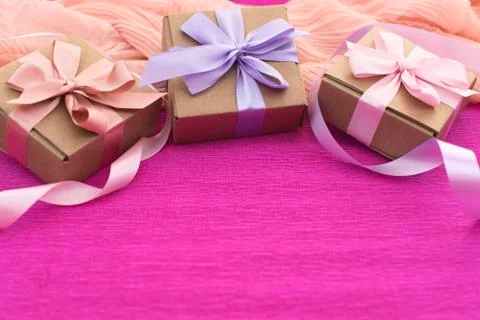 Festive composition three Kraft boxes with gifts on bright pink background. Stock Photos