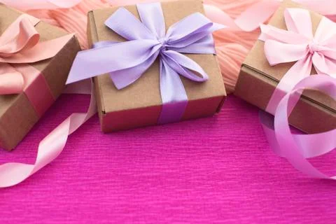 Festive composition three Kraft boxes with gifts on bright pink background. Stock Photos