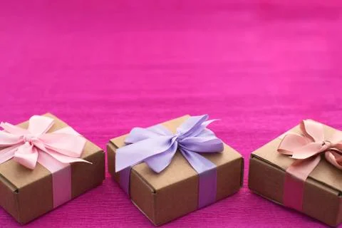 Festive composition three Kraft boxes with gifts on bright pink background. Stock Photos