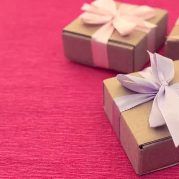 Festive composition three Kraft boxes with gifts on bright pink background. Stock Photos