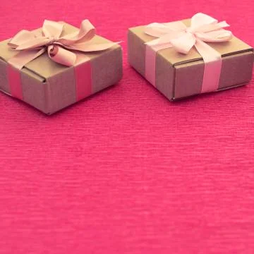 Festive composition three Kraft boxes with gifts on bright pink background. Stock Photos