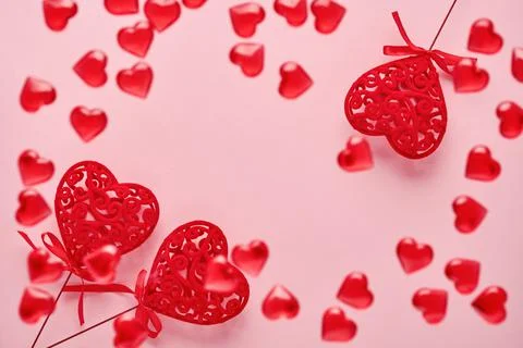 Festive composition with three red openwork hearts and small flying hearts on Stock Photos