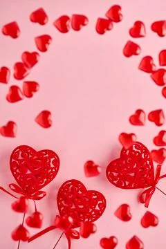 Festive composition with three red openwork hearts and small flying hearts on Stock Photos