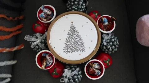 A festive cookie tin with a delicate pine tree design, surrounded by cheerful ho Stock Footage 294704883