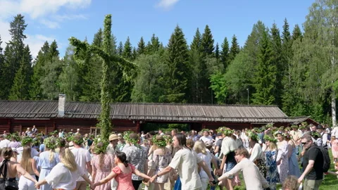 Festive crowd dancing around flower adorned maypole during traditional Mids.. Stock Footage 310519860