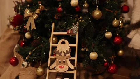 Festive decoration under Christmas tree with reindeer sign and ornaments in cozy 库存影片 323765747