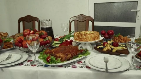 Festive dining table adorned with a variety of traditional dishes, fruits, and Vídeo Stock 332736954