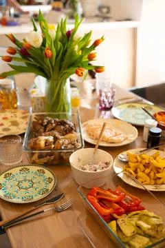 Festive dining table with home-cooked meals and tulip bouquet Stock Photos