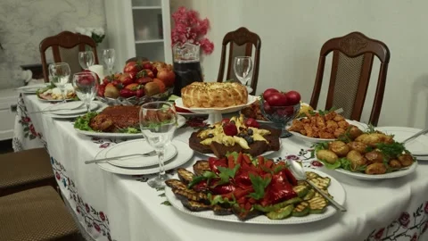 Festive dining table set with various traditional dishes, fruits, and drinks, Vídeo Stock 332736953