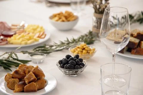 A festive dining table is set with white plates, wine glasses and greenery Stock Photos