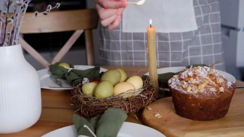 Festive dinner table setting for Easter. A woman lights a candle on the table Stock Footage 265947920