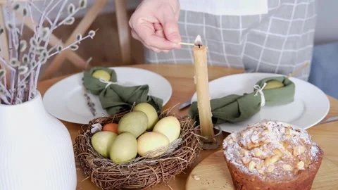Festive dinner table setting for Easter. A woman lights a candle on the table Stock Footage 269347924