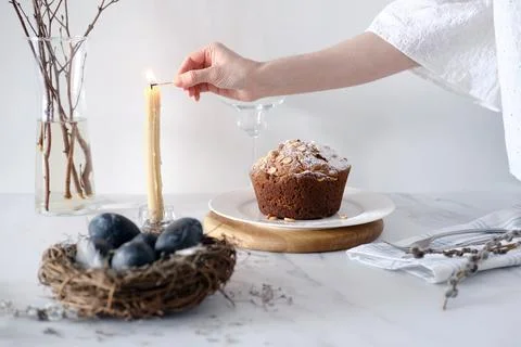 Festive dinner table setting for Easter. A woman lights a candle on the table Foto stock