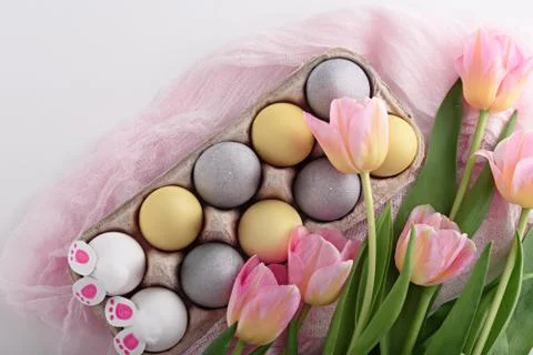 Festive Easter composition of Easter eggs, tulips, rabbit paws on white backg Stock Photos