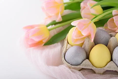 Festive Easter composition of Easter eggs, tulips on white background Stock Photos