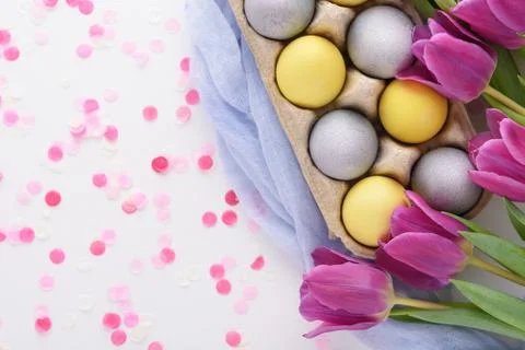 Festive Easter composition of purple tulips and yellow and blue Easter eggs w Stock Photos