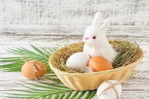 Festive easter composition with small bunny sitting in a basket with easter.. Stock Photos