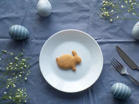 Festive Easter table setting with cookie and flowers on blue background Stock Photos