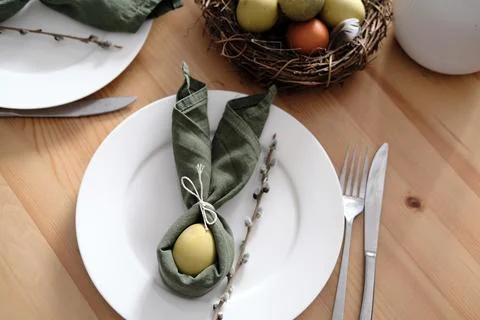 Festive Easter table setting with Easter bunny made of linen napkin and egg. Top Stock Photos