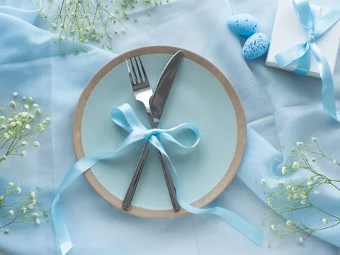 Festive Easter table setting with eggs, flowers and gift box on brown background Stock Photos