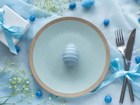 Festive Easter table setting with eggs, flowers and gift box on brown background Stock Photos