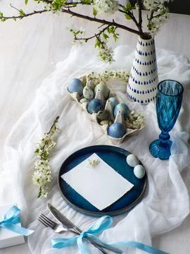 Festive Easter table setting with eggs, flowers and gift box on white background Stock Photos