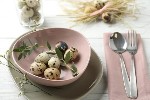 Festive Easter table setting with quail eggs and floral decor on wooden backg Stock Photos