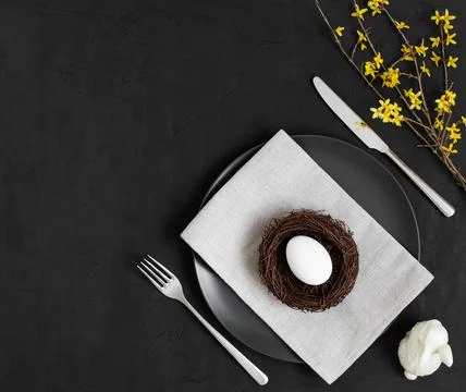 Festive Easter table setting with white egg in a nest on a plate, rabbit Stock Photos