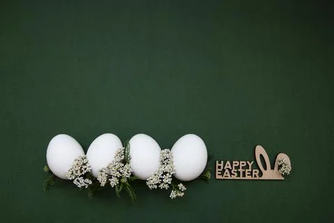 Festive Easter white eggs with white small flowers on a green background. Stock Photos