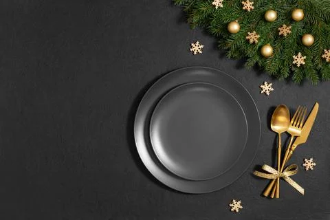 Festive empty table setting with golden Christmas decorations on a black back Stock Photos