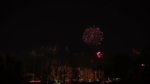 Festive fireworks on dark background of night sky over houses with illumination. Stock Footage 196245867