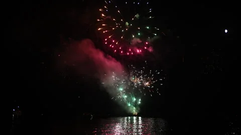 Festive fireworks exploding over dark water, creating glowing reflections. 스톡 동영상 343273551