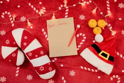 Festive flat lay with a blank Dear Santa letter, red pen, candy cane pillow.. Stock Photos