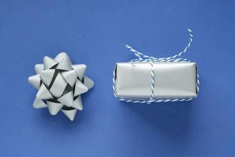 Festive flat lay: a gift in a silver box and a silver bow to decorate the gif Stock Photos