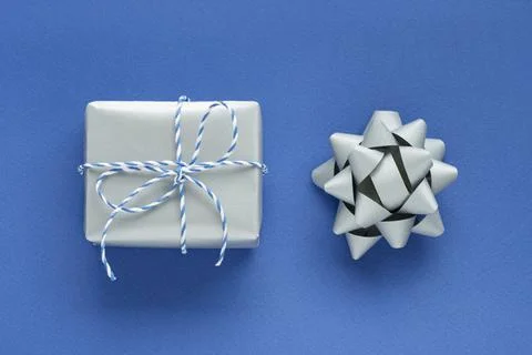 Festive flat lay: a gift in a silver box and a silver bow to decorate the gif Stock Photos