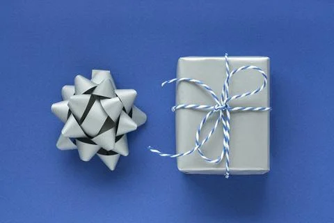 Festive flat lay: a gift in a silver box and a silver bow to decorate the gif Stock Photos