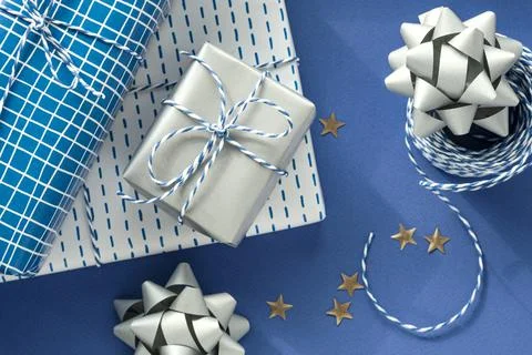 Festive flat lay: gift in white or silver box, blue gift rope, silver bows to Stock Photos