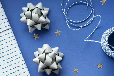 Festive flat lay: gift in white or silver box, blue gift rope, silver bows to Stock Photos