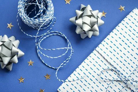 Festive flat lay: gift in white or silver box, blue gift rope, silver bows to Stock Photos