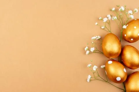 Festive flat lay with golden easter eggs and Gypsophila flowers on brown ba.. Stock Photos