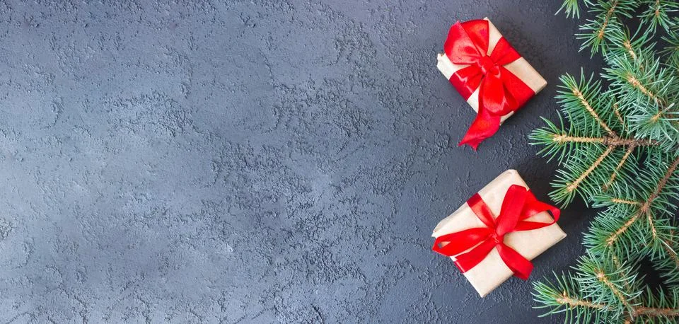 Festive gift boxes with spruce branches on concrete background. Stock Photos