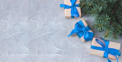 Festive gift boxes with spruce branches on concrete background. Stock Photos