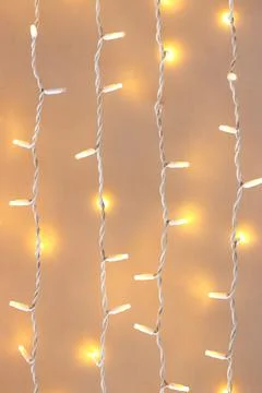Festive LED string lights hanging on a light background Stock Photos
