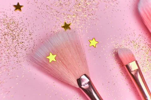 Festive magic make up brushes on pink background. Stock Photos