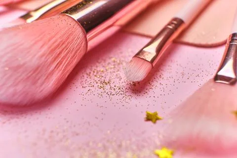 Festive magic make up brushes on pink background. Stock Photos