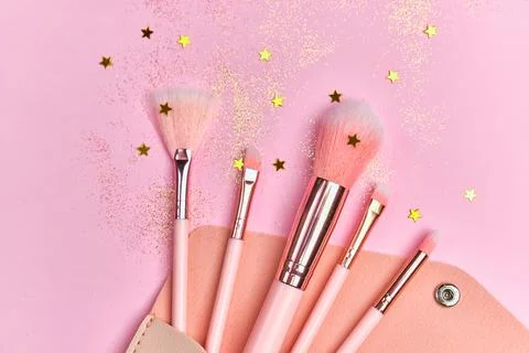Festive magic make up brushes on pink background. Stock Photos